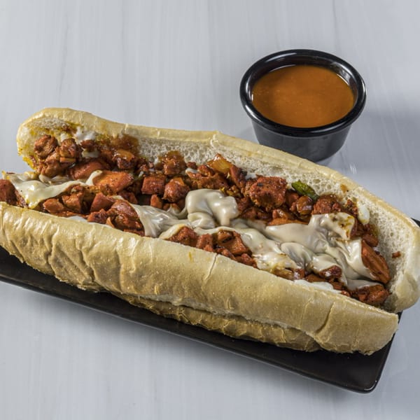 A Blazing Hot Halal Grill chicken cheesesteak with melted cheese and a side of sauce.