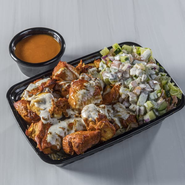 Halal chicken and rice platter with white sauce, salad, and a side of orange sauce.